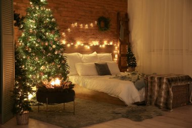 Karanlık yatak odasının içinde Noel ağaçları ve parlak ışıklar var.