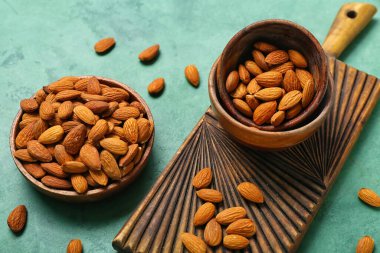 Yeşil zemin üzerinde bir kase badem olan tahta