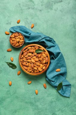 Yeşil arka planda bir kase badem.