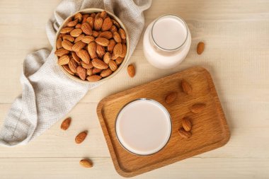 Cam pano, badem sütü ve ahşap arka planda fındık.