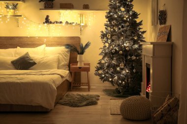 Yatak odasının içinde Noel ağacı, raflar ve geceleri parlayan ışıklar var.