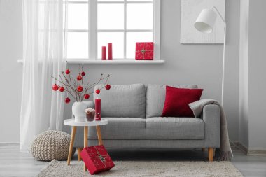 Oturma odasının içinde kanepe, ağaç dalları ve vazoda Noel topları var.