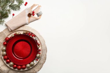 Beyaz arkaplanda Noel topları, kızılcık ve köknar dalları olan masa ayarı