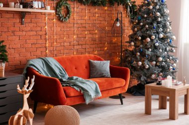 Oturma odasının içinde kanepe, Noel ağacı ve parlayan ışıklar var.