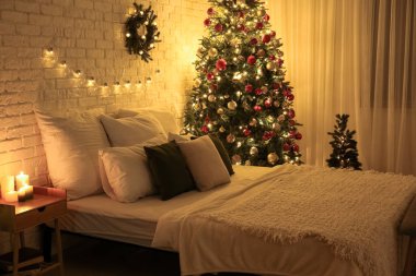 Yatak odasının içinde Noel ağaçları, çelenkler ve geceleri parlayan ışıklar var.