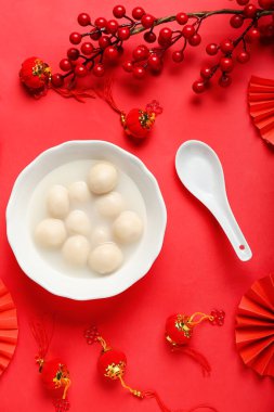 Kırmızı arka planda bir kase lezzetli tangyuan ve Çin dekoru. Dongzhi Festivali