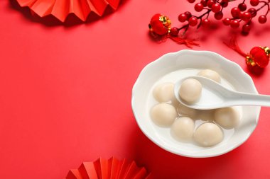 Kırmızı arka planda bir kase lezzetli tangyuan ve Çin dekoru. Dongzhi Festivali