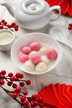 Bir kase Tangyuan, fincan, çaydanlık ve arka planda Çin dekoru. Dongzhi Festivali