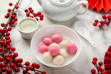 Bir kase Tangyuan, fincan, çaydanlık ve arka planda Çin dekoru. Dongzhi Festivali