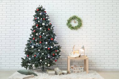 Işıl ışıl Noel ağacı, çelenk ve masa olan oturma odasının içinde.