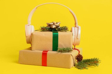 Noel hediyeli kulaklıklar ve sarı arka planda köknar dalları