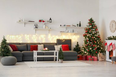 Oturma odasının içinde kanepe, Noel ağaçları ve şömine var.