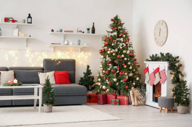 Oturma odasının içinde kanepe, Noel ağaçları ve şömine var.