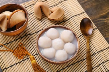 Bambu hasırı, bir kase tangyuan ve ahşap arka planda fal kurabiyesi. Dongzhi Festivali