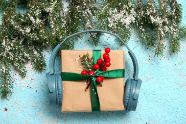Noel hediyeli kulaklıklar, köknar dalları ve arkaplanda kar.