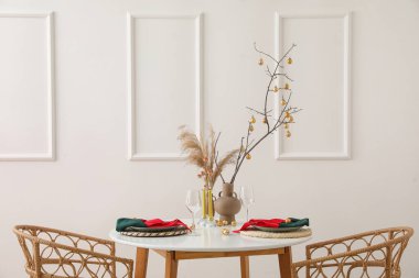 Ağaç dalları olan vazolar, otlar ve yemek masasındaki Noel topları.