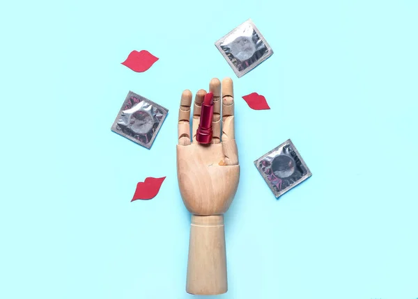 带口红 避孕套和蓝底纸唇的木制手部 性别概念 — 图库照片