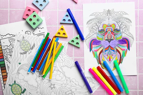 Coloring pages, felt-tip pens and toys on pink tile background