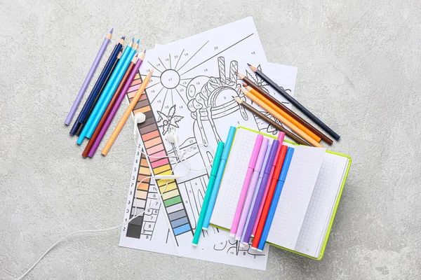 Coloring pages, felt-tip pens, pencils and notebook on grunge background