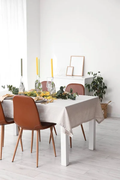 Table with festive setting and floral decor in light room interior