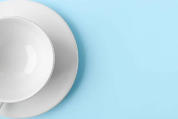 stock image White cup with saucer on blue background, closeup