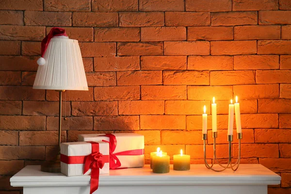 Lampe Mit Weihnachtsmütze Weihnachtsgeschenke Und Brennende Kerzen Auf Kaminsims Nahe — Stockfoto