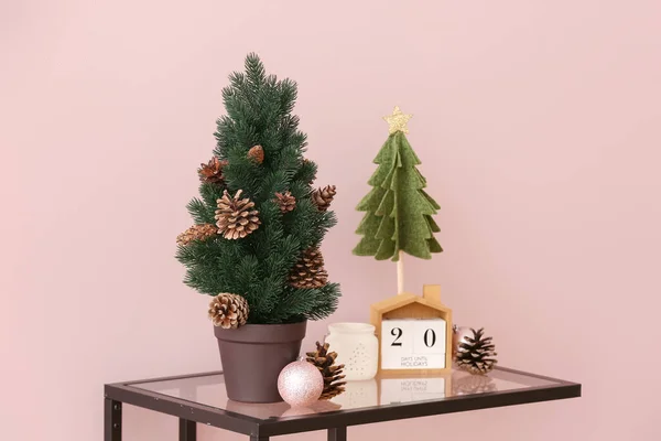 Kis Karácsonyfák Fenyőtobozokkal Kocka Naptárral Asztalon Rózsaszín Fal Mellett — Stock Fotó