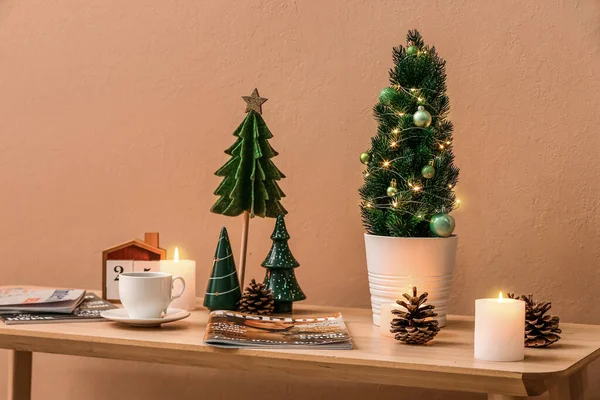 Kis Karácsonyfák Gyertyákkal Csésze Kávéval Magazinokkal Asztalon Bézs Fal Mellett — Stock Fotó
