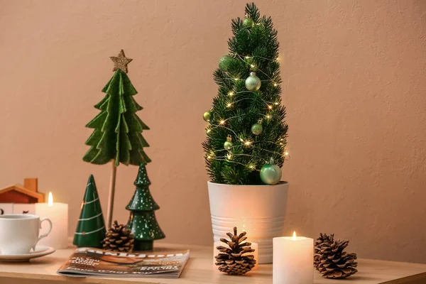 Small Christmas Trees Fir Cones Candles Magazine Table Beige Wall — Stock Photo, Image