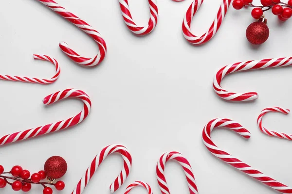 白い背景においしいキャンディーの杖とクリスマスの装飾で作られたフレーム — ストック写真