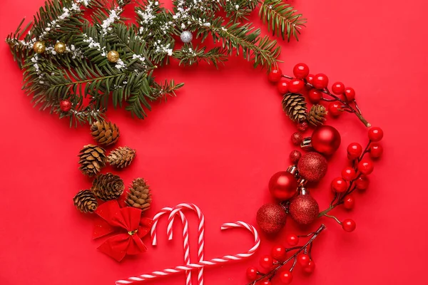 赤い背景にクリスマスの装飾 モミの枝やキャンディーの杖で作られたフレーム — ストック写真