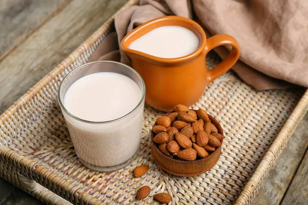 stock image Tray with jug, glass of healthy almond milk and nuts on wooden table, closeup