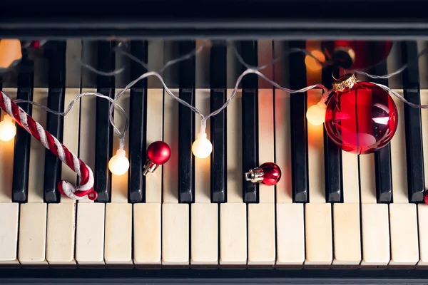 红色圣诞球 钢琴键上闪烁着彩灯 — 图库照片