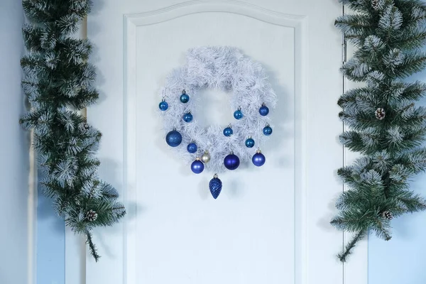 Λευκή Πόρτα Χριστουγεννιάτικο Στεφάνι Και Έλατο Κλαδιά Στην Αίθουσα Closeup — Φωτογραφία Αρχείου