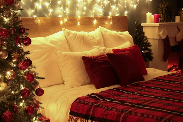 夜の寝室で輝くクリスマスライト付きの大きなベッド — ストック写真