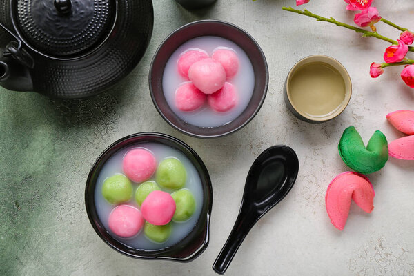 Bowls of tangyuan, fortune cookies, cup and teapot on grunge background. Dongzhi Festival