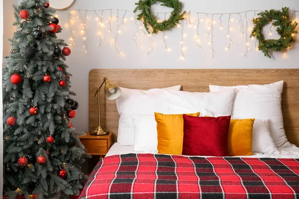 Interior of bedroom with Christmas tree, wreaths and glowing lights