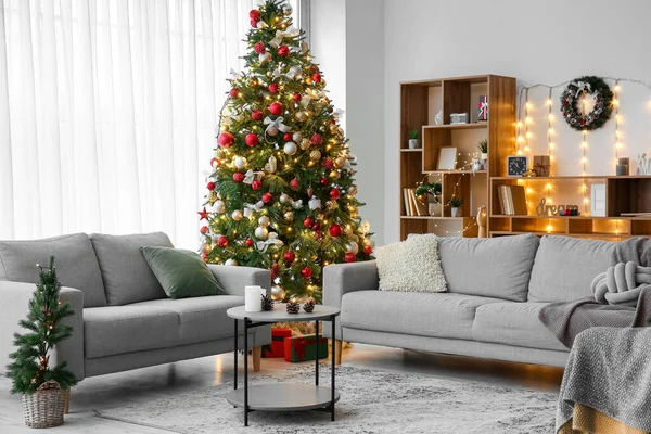 Interior of living room with sofas, Christmas trees and glowing lights