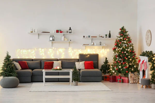 Interior of living room with sofa, Christmas trees and fireplace