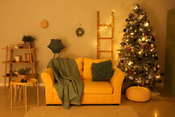 Interior of living room with sofa, Christmas tree and glowing lights at night