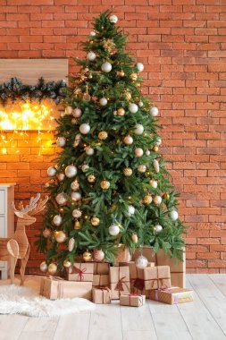 Hediyelerle parlayan Noel ağacı ve tuğla duvarın yanında tahta ren geyiği