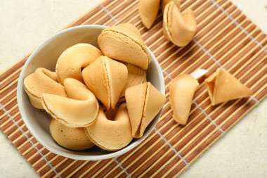 Arka planda bir kase fal kurabiyesi olan bambu hasırı, yakın plan.