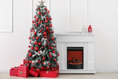 Işık duvarının yanında hediyeler ve şömineyle süslenmiş Noel ağacı.