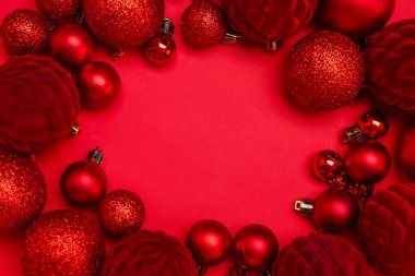 Renkli arkaplanda kırmızı Noel toplarından yapılmış çerçeve