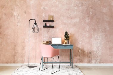 Dizüstü bilgisayarı, Noel ağacı ve pembe duvarlı hediyeleri olan bir iş yeri.