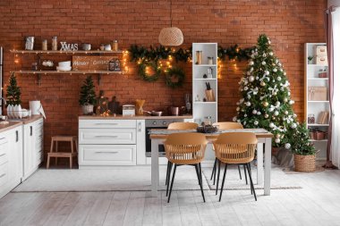 Işıl ışıl Noel ağaçları, yemek masası ve tezgahları olan mutfağın içi.