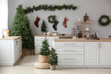 İçinde Noel ağaçları, beyaz tezgahlar ve çoraplar olan mutfağın içi.
