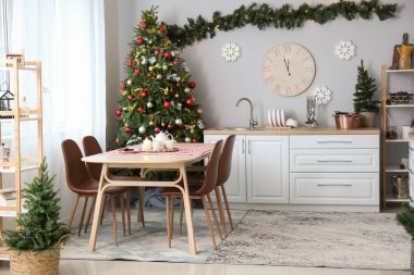 Mutfağın içinde Noel ağaçları, yemek masası ve büyük saat var.