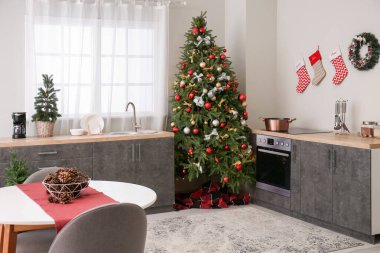 Mutfağın içinde Noel ağaçları, tezgahlar ve yemek masası var.