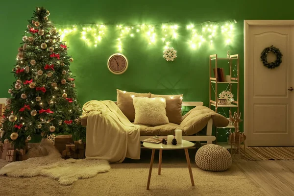 Interior of dark living room with Christmas tree, couch and glowing lights